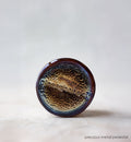 Round metallic object with textured surface on a light gray background