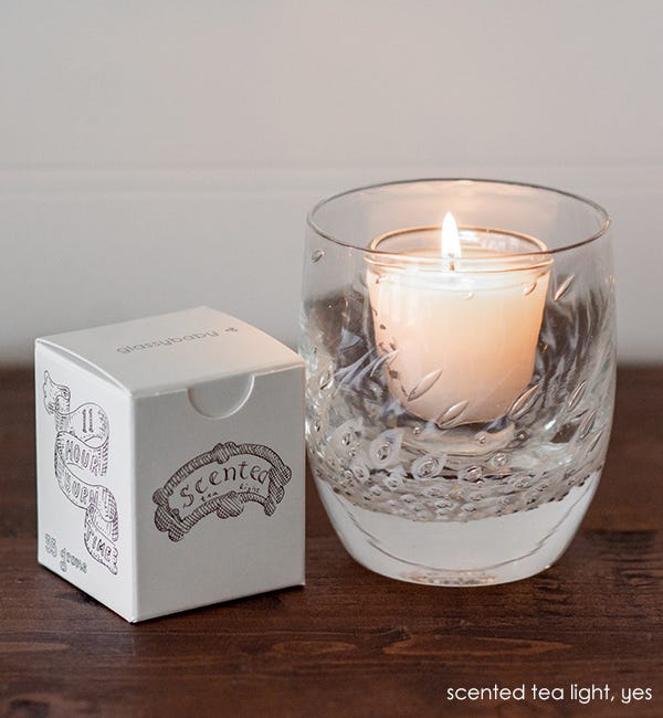 glassybaby scented tea light lit in yes, sitting next to scented tealight box.