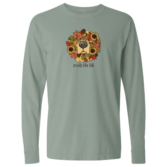 A sage green long-sleeve t-shirt with a graphic of a dog's face surrounded by autumn leaves and sunflowers, with the text 'smells like fall' printed below the graphic.