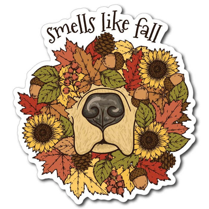 A die-cut sticker featuring a stylized dog face surrounded by autumn leaves, sunflowers, acorns, pinecones, and berries, with the text 'smells like fall' above, shown on a plain white background.