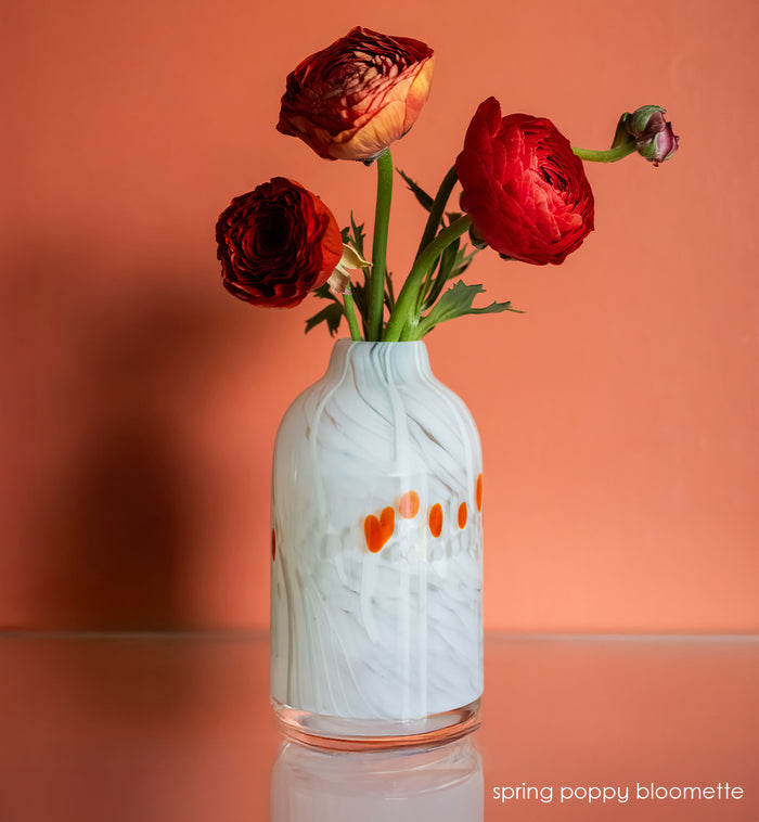 white bloomette vase with red spots with red flowers on wood table