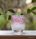 sunday brunch pink and purple topped hand-blown glass votive candle holder, on a windowsill looking over a green yard.
