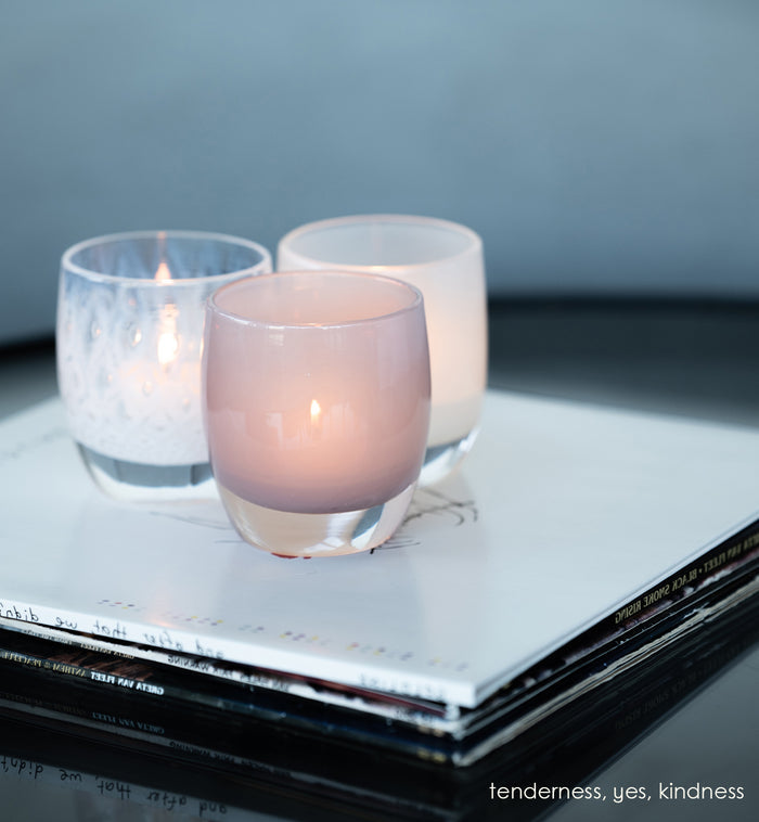 tenderness, a soft-purple hand-blown glass votive candle holder. paired with yes and kindness  on a stack of records.
