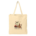 A beige canvas tote bag with a printed graphic of a dog wearing sunglasses and a plaid blanket, next to a basket of red apples, with the text 'the dog days of Fall' below.