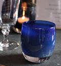 zen, midnight blue textured, hand-blown glass votive candle holder on a wedding table with a wine glass and menu.